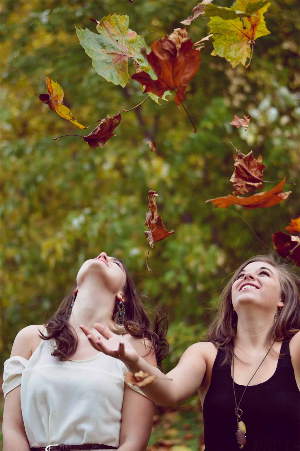 Photo deux femmes dans la nature regardant les feuilles d'arbres tomber